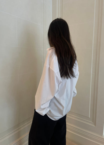 White poet shirt collar detail with red signature embroidery